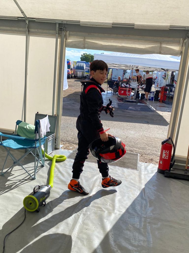 Le jeune pilote quitte le paddock, casque à la main.