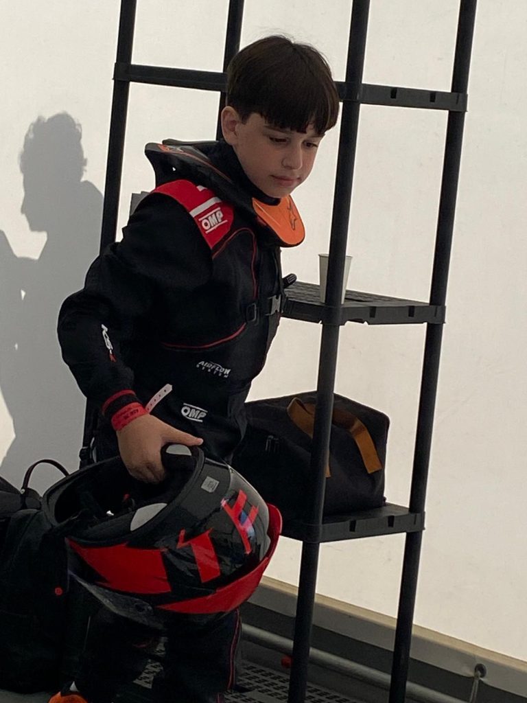 Le jeune pilote en combinaison tient son casque avant une séance.